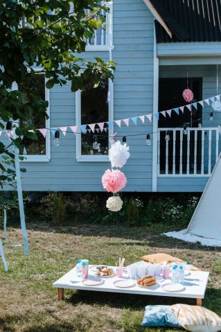 Outdoor garden party setup with decorations and a wooden table for a cozy celebration.