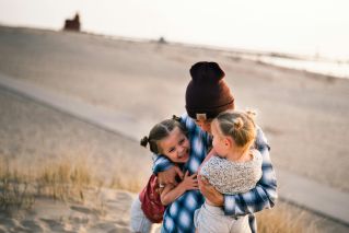 A loving family moment captured on a sunny day at a beach in Holland, MI.