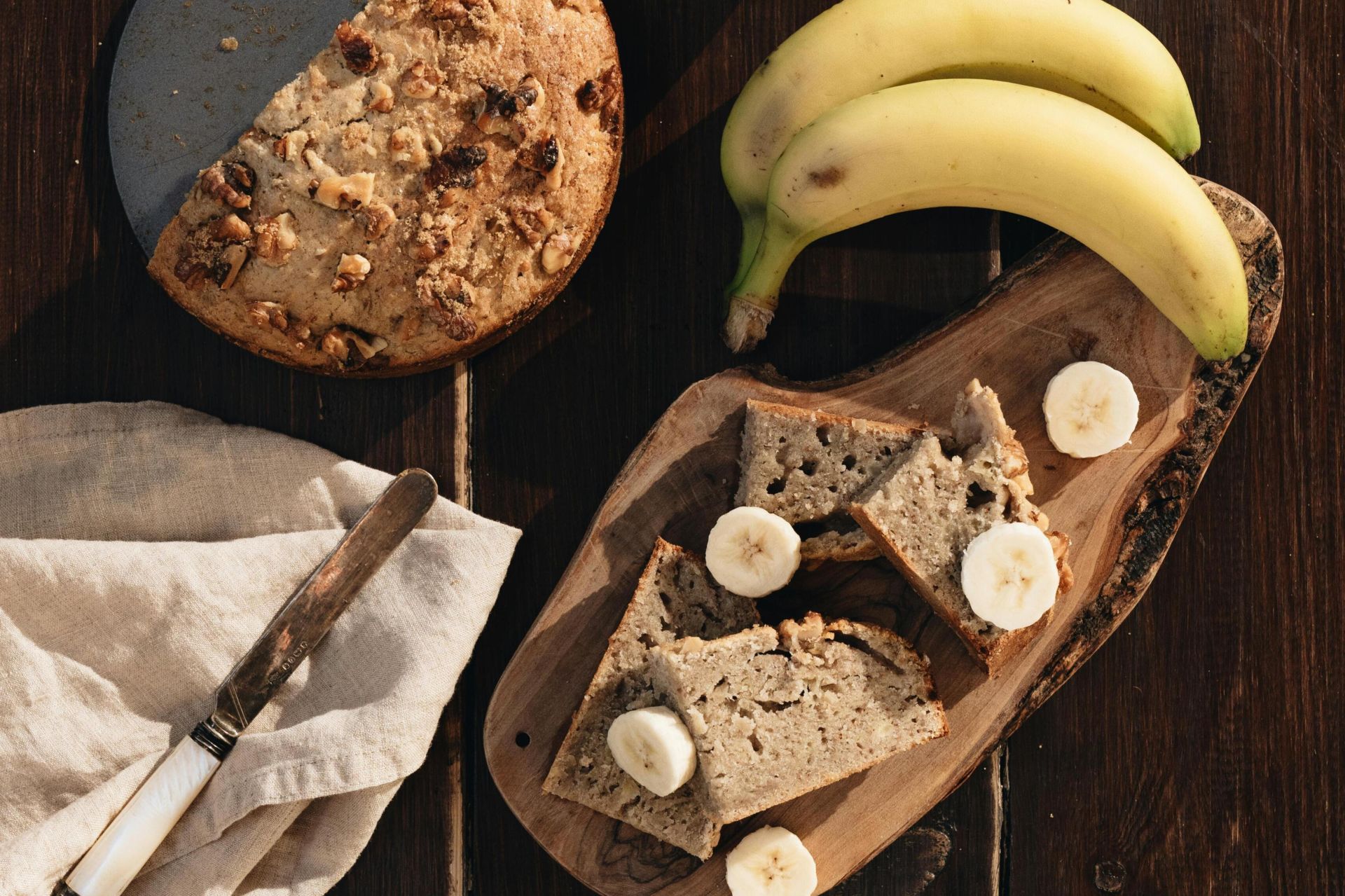 Delicious homemade banana bread with fresh bananas and slices on a wooden table.