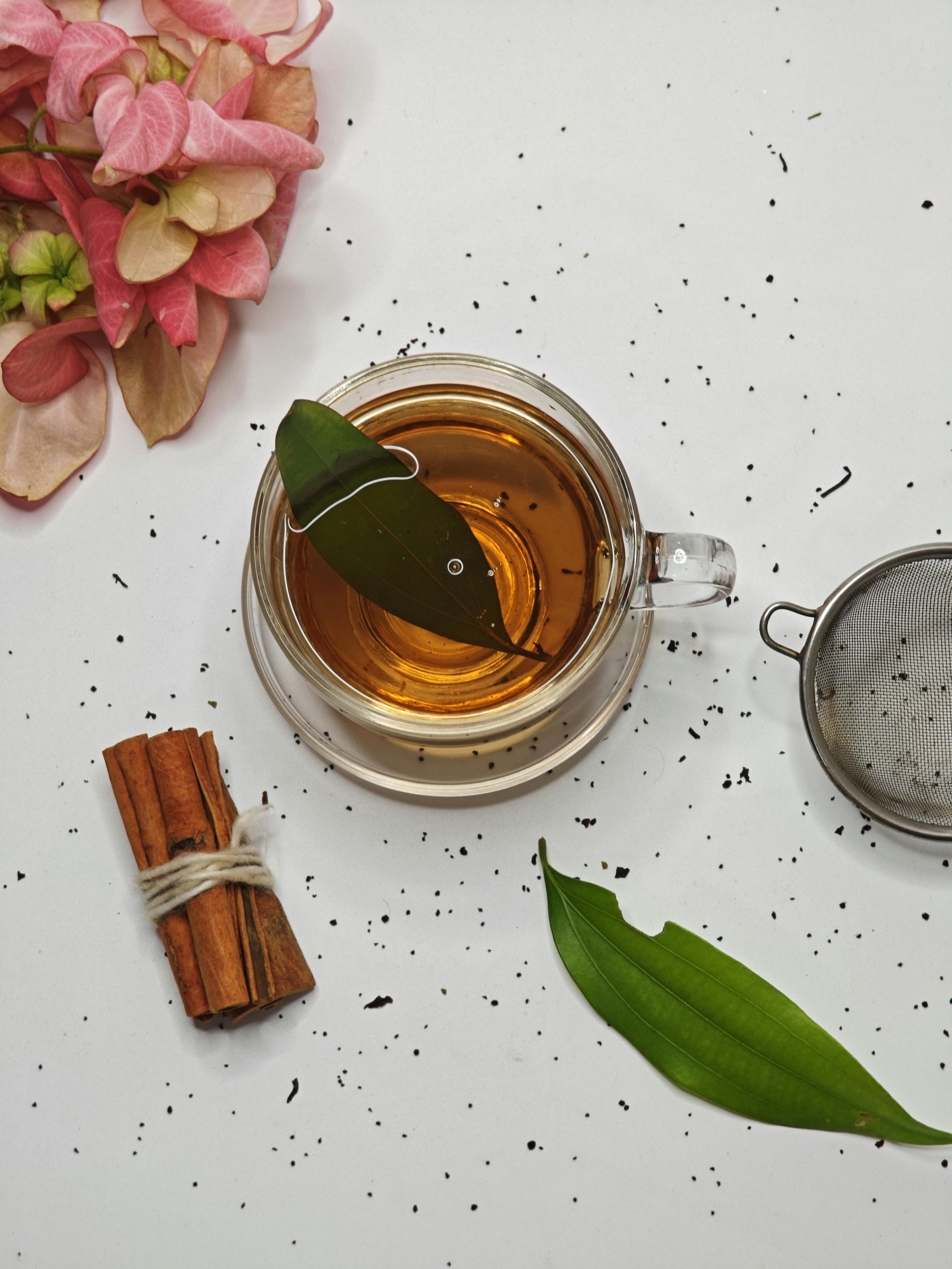 Overhead shot of herbal tea with cinnamon and flowers on a white background.