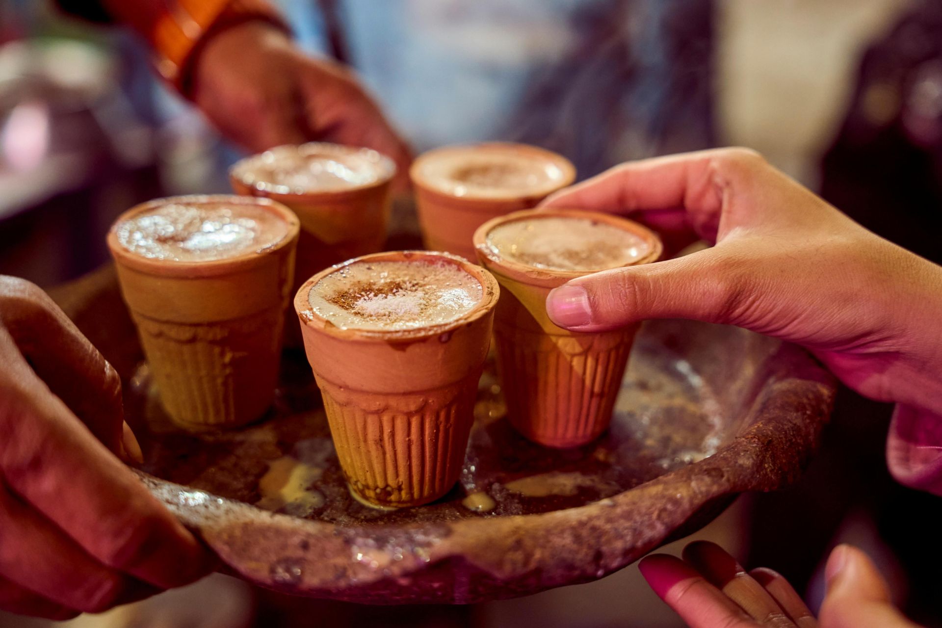 Close-up of masala chai served in clay cups by a street vendor, capturing authentic Indian culture.